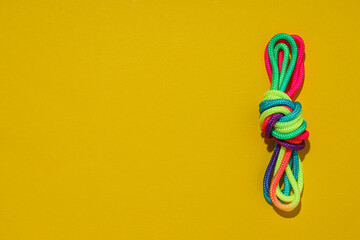 A knot of multi-colored laces on a yellow background. Place for text