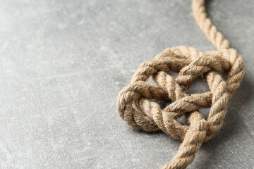 Knotted thick rope close-up on gray background. Place for text