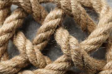 Thick knotted rope close-up on gray background