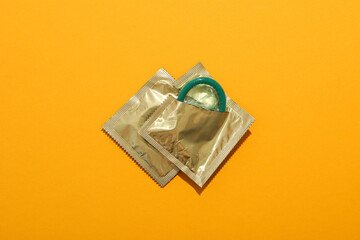 Green condoms on a yellow background close-up