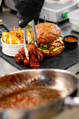 chef cooking fast food set on plate. burger, potato chips, french fries, chicken wings, fried cheese