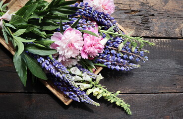 A bouquet of lupines and peonies . Multicolored summer flowers pink and purple on wooden background