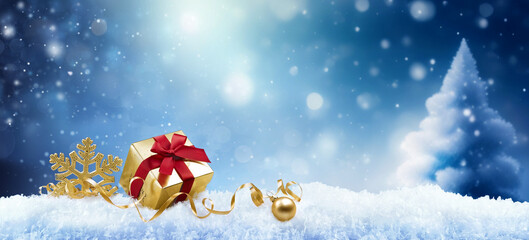 Christmas background with a golden gift, a snowflake and a ball in the snow in forest against a...
