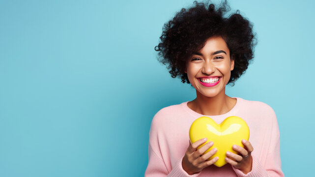 Smiling woman holding small plastic heart isolated on blue background. AI Generated.