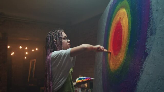 Concentrated artist drawing rainbow target with paints
