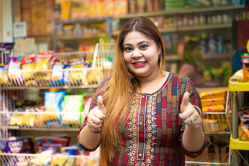 Indian woman showing thumps up at grocery shop.