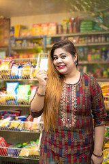 Indian woman showing bank card at grocery shop.