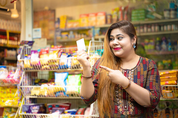 Indian woman showing bank card at grocery shop.
