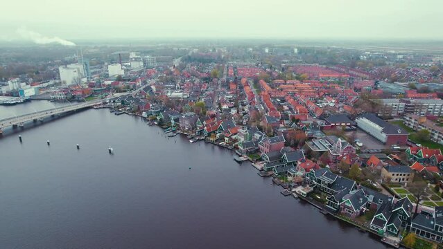 Aerial shot of the Koog aan de Zaan town with a river and buildings with red roofs. High quality 4k footage