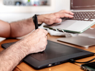 Man operating computer and drawing with digital pen on graphics tablet