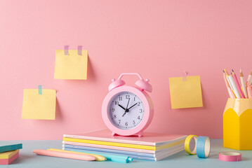 Back to school concept. Photo of color stationery on blue desk alarm clock over stack of copybooks...