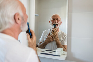 Hand, beard and shaving with an electric razor with a mature man in the bathroom. Face, grooming and hygiene with a mature male in the bathroom to shave for hair removal.