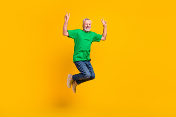 Fototapeta na wymiar Full length photo of active energetic man jumping hands fingers demonstrate v-sign isolated on yellow color background