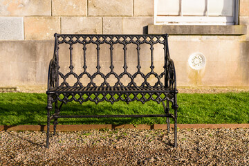 Cast iron two-seater garden bench on a gravel path.