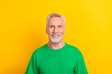 Photo of cheerful thoughtful man wear green t-shirt looking up empty space isolated yellow color background