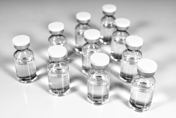 Glass vials with transparent liquid medication on a light background