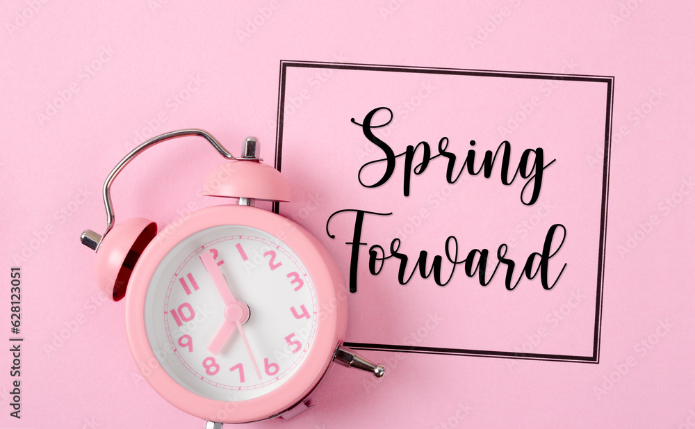Fototapete the spring forward with an alarm clock on pink color background.