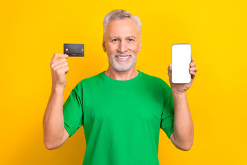 Portrait of handsome person hands hold showing plastic debit card empty space smart phone display isolated on yellow color background