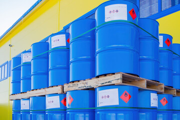 Barrels with chemical products. Casks stored outdoors. Pallets with blue barrels near warehouse....
