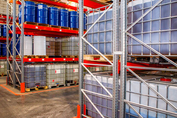 Warehouse business. Warehouse for chemical products. Plastic barrels with different liquids. Production and storage chemicals. Pallets with tanks in lathing. Warehouse of toxic substances with racks - obrazy, fototapety, plakaty