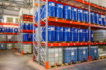 Storehouse with barrels. Interior storage area of enterprise. Blue barrels on pallets. Multi-tier warehouse racks. Storehouse in industrial hangar. Place to store finished products in manufactory - Powered by Adobe