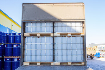 Truck body rear view. Plastic industrial containers on pallets. Barrels for liquids in lathing. Open body of truck loaded with goods. Container for transportation of fuel. Reservoir for chemistry