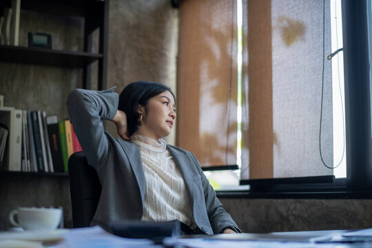 Asian businesswoman resting her eyes from the screen as she twists herself to relieve fatigue.