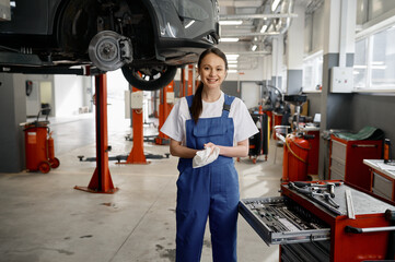 Portrait of beautiful smiling woman mechanic wiping hands with rag