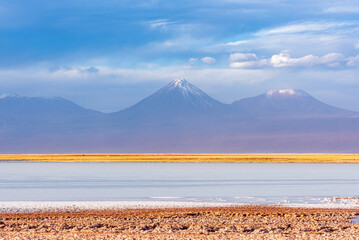 Snowy volcano peaks viewed from Tebinquinche lagoon in Atacama desert