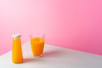 Orange juice on white table against pink background