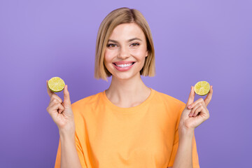 Photo of charming beautiful woman blonde bob hair wearing yellow t shirt holding two halves pour lime isolated on purple color background