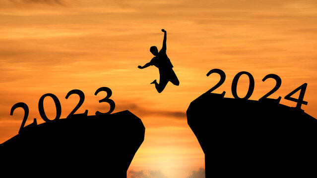 Concept Happy new year 2024 Silhouette image of happy man joyful leaping with Happiness 2023 up to 2024 on beautiful sky sunrise.