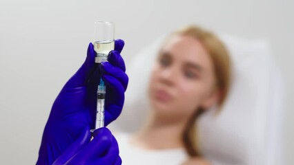 Woman's hands seen drawing liquid from a vial into a syringe - isolated close up