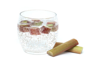 Glass of water with rhubarb pieces over white
