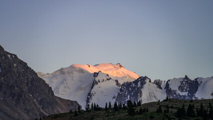 snowy mountain peaks. the green plateau of the foothills. summer mountains