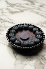 Tartlet with fresh blueberry on white marble background, top view.