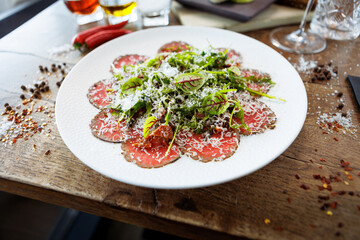 Beef carpaccio. Borettane onion, sun-dried tomato, truffle dressing, arugula salad, parmesan cheese. Italian traditional antipasti snacks served for lunch with wine in modern gourmet restaurant