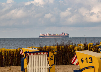 Containerschiff am Horizont vor Strandkörben