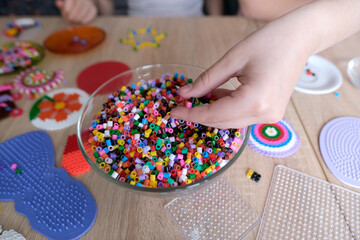 close-up of children's hands creating perler bead patterns, make crafts using thermomosaic...