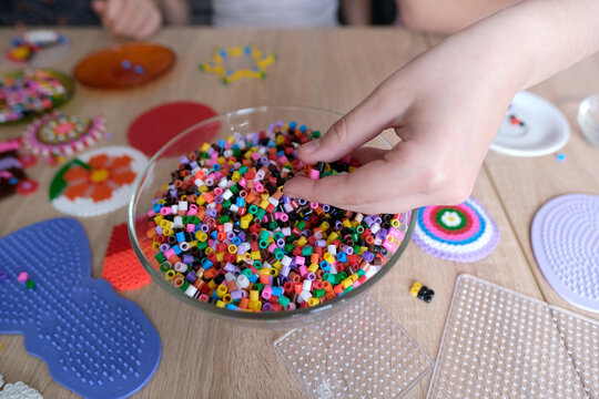 close-up of children's hands creating perler bead patterns, make crafts using thermomosaic technique, beading patterns, perler bead art, concept development of fine motor skills, thermo mosaic ideas