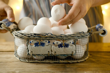 mesh vintage metal basket with fresh white chicken eggs on wooden table, valuable food product,...