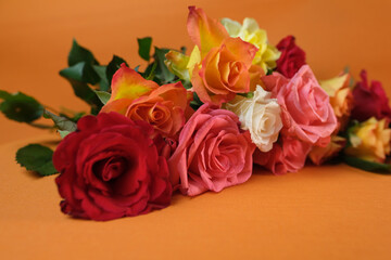 bouquet of yellow, red, pink roses with a copy space for the designer, flowers for professional holiday on an orange background, concept of mother's, Valentine's day, birthday, selective focus