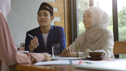 A group of successful upwardly mobile Asian Muslim friends relish a tranquil coffee shop gathering on a bright and joyful sunny day