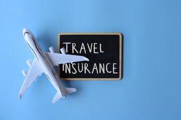 Top view image of toy plane and chalkboard with text TRAVEL INSURANCE on blue background.