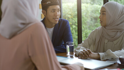 A group of successful upwardly mobile Asian Muslim friends relish a tranquil coffee shop gathering on a bright and joyful sunny day