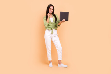 Full length photo of optimistic clever nice woman wear green shirt holding laptop finger on lips isolated on beige color background
