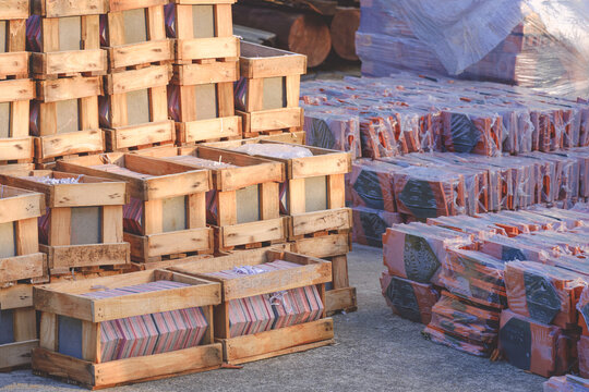 Stack of imbrication clay tiles roof for roofing of Thai temple church in wooden boxes with many bundles of terracotta roof tiles on the floor in construction site