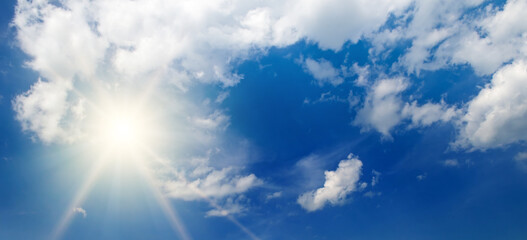 Naklejka na ściany i meble Bright sun, blue sky and clouds. Wide photo.