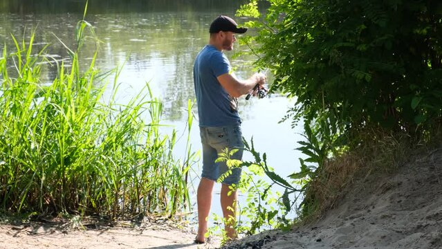 A man is fishing on the river bank for spinning. Active fishing. Slow motion.
