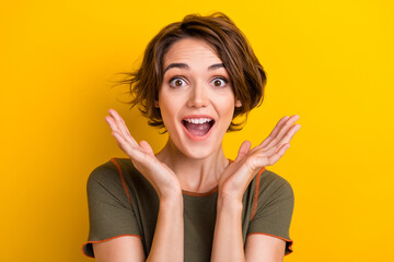 Photo of adorable impressed lady wear khaki t-shirt smiling rising arms isolated yellow color...